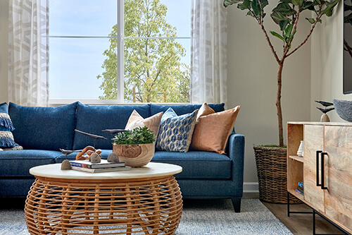 living room with blue couch and woven coffee table